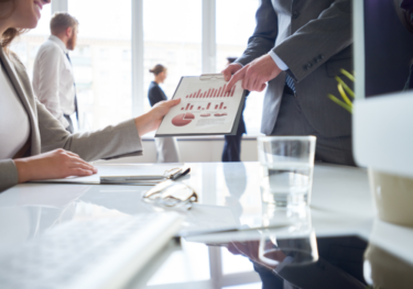 Image of people discussing graphs, pointing at a report