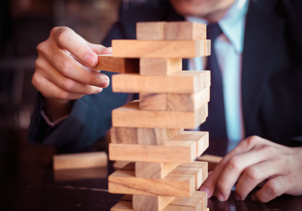 Two business persons playing Jenga , pulling wooden blocks