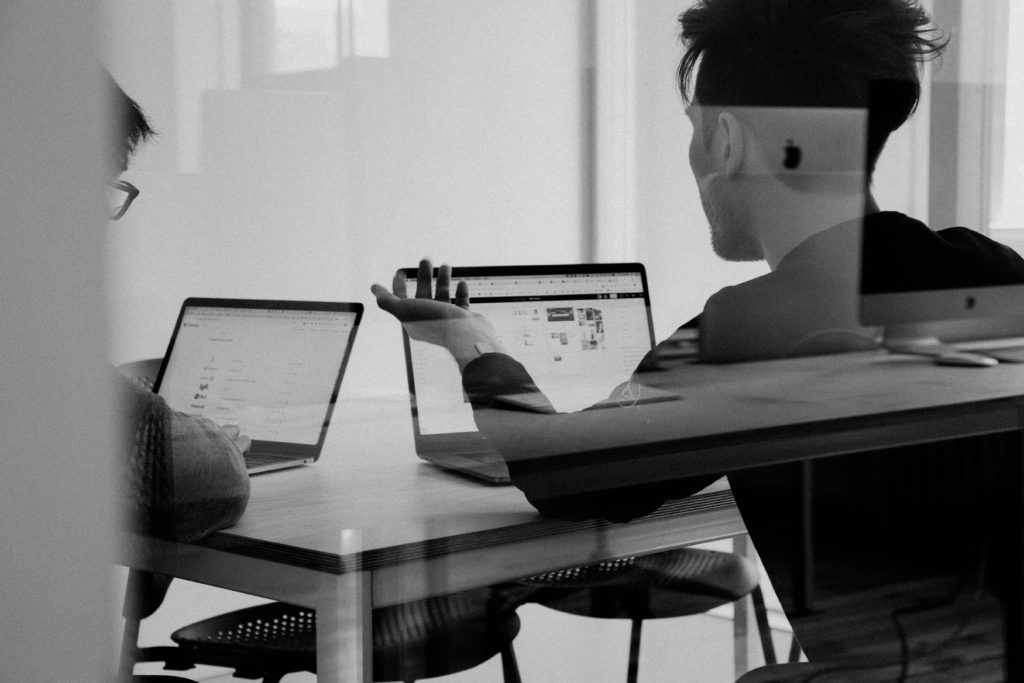 people in meeting room in front of laptops people in meeting room in front of laptops