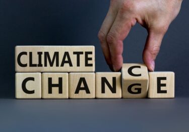 Climate change symbol. Hand flips a cube and changes words 'climate change' to 'climate chance'