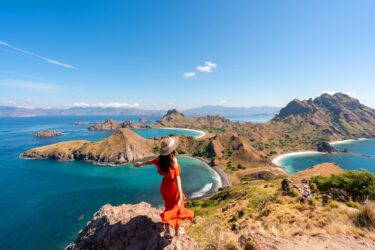 Women with a hat at the top of a scenic mountain overlooking waterway