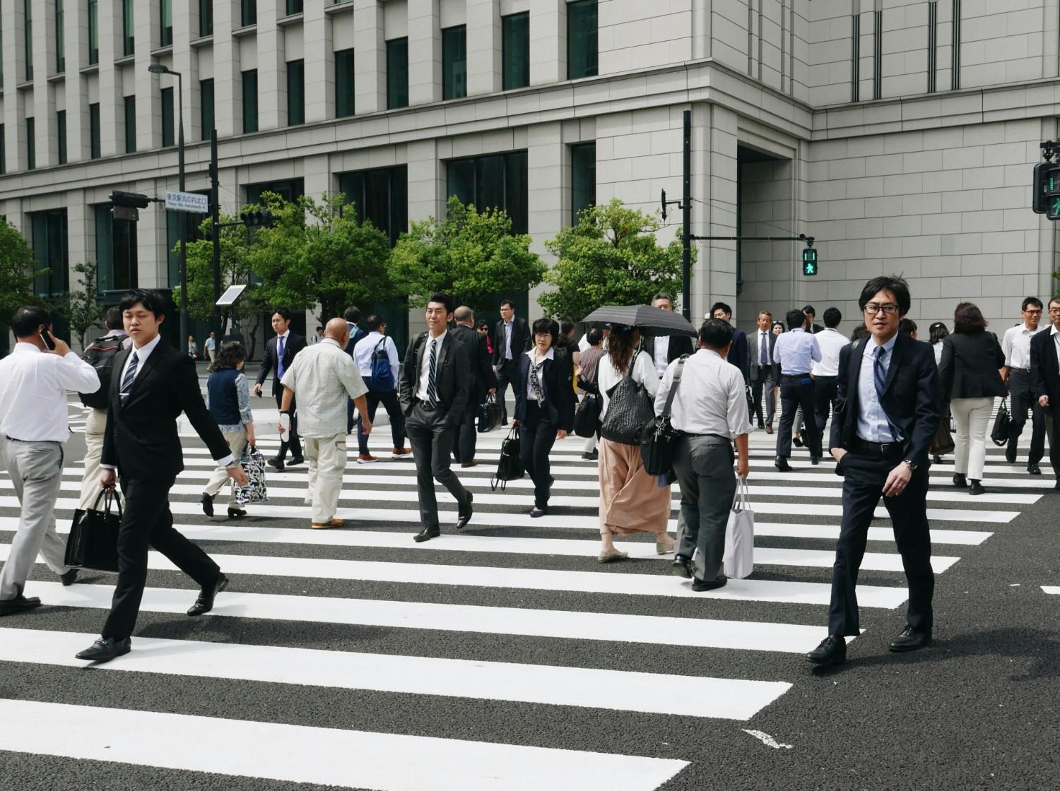 a group of people walking across a crosswalk in japan